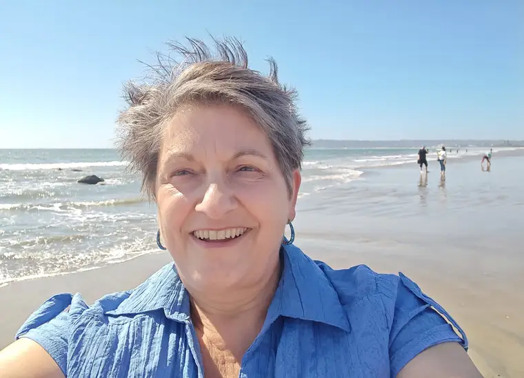 Sandy smiling on the beach on a bright, breezy day